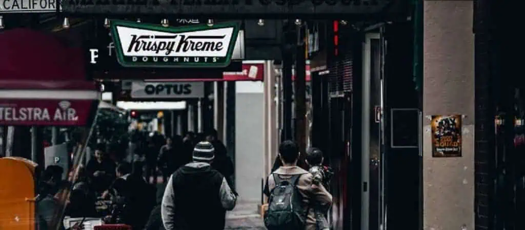 Shoppers walking down a busy street during the day with storefronts and window displays